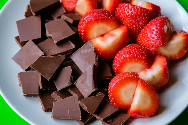 Londra İngiltere, 15 Temmuz 2025, Dilimlenmiş taze organik çilekler Kırık Süt Çikolatası ile