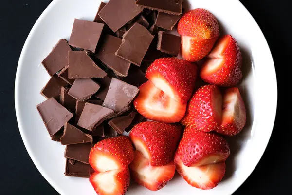 Londra İngiltere, 15 Temmuz 2025, Dilimlenmiş taze organik çilekler Kırık Süt Çikolatası ile