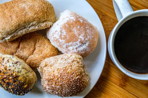 Londra İngiltere, 15 Temmuz 2025, Fırında pişmiş Mini Ekmek Ekmekleri ve bir kupa siyah kahve.