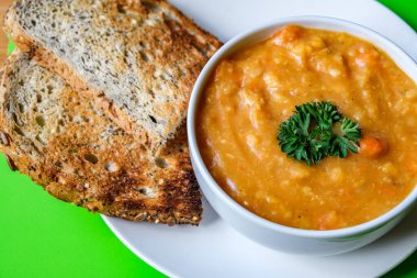 Londra İngiltere, 16 Temmuz 2025, Maydanozla süslenmiş bir kase sıcak vejetaryen mercimek çorbası