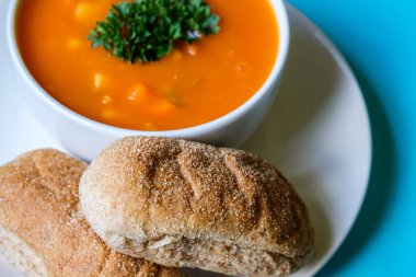 Londra İngiltere, 16 Temmuz 2025, maydanozla süslenmiş bir kase sağlıklı sebze çorbası ve kahverengi denizaltı Rolls Roll 'u.