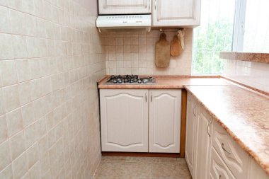 Modern dar, modern, çağdaş mobilyaları, duvarında bej seramik fayansları, gaz sobası ve pencere manzaralı kompakt mutfağın iç tasarımı..