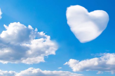 Açık mavi gökyüzünde yüzen, ufuk çizgisi ufuk çizgisi arkaplan arkaplanı olan, kalp şeklinde beyaz kabarık kümülüs bulutunun parlak manzarası..