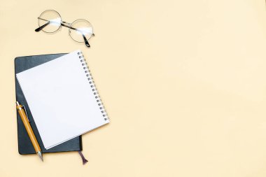 Siyah boş defter, kalem, gözlük, bej arka planda gözlük. Üst düzey masa düzenlemesi. Zaman yönetimi, planlama konsepti. Asgari biçim, kopyalama alanı ve şablon logo tasarımı ile modelle.