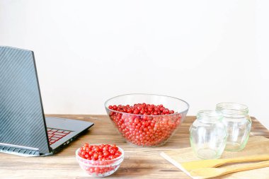 Ev mutfağındaki kavanozlarda reçel yapmaya hazırlanan kırmızı frenk üzümü. Yaz meyveleri soymak, yemek pişirmek, yemek tarifleri. Doğal, sağlıklı donmuş dut, vitamin açısından zengin ahşap masa..