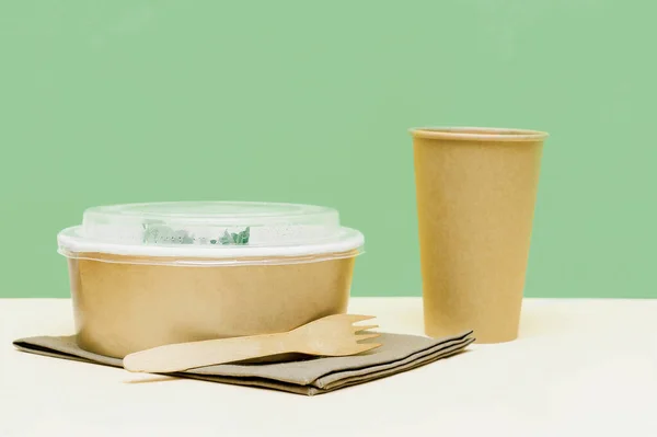 Healthy food lunch in kraft paper carton eco friendly box disposable bowl packaging container, cup on green background. chicken, eggs, greens. Take away delivery. environment protection.