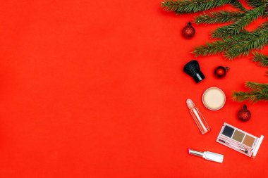 Christmas beauty cosmetics composition with brushes tools and accessories with new year fir spruce branches decorations on red background. Stylish concept. Flat lay, mock up top view with copy space.