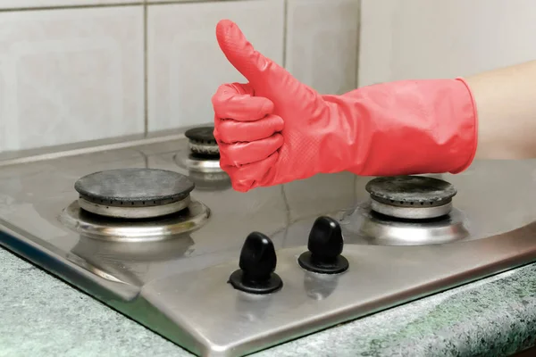 Cleaning dirty gas stove from grease, food leftovers deposits. woman\'s hand in protective glove washing kitchen stove,toned trendy color of 2023 viva magenta. home cleaning service concept.