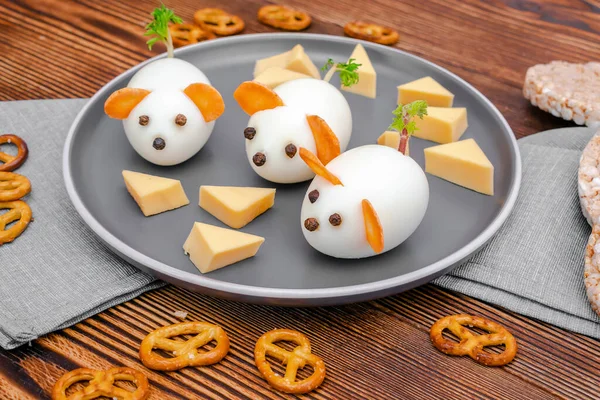 Small chicken eggs mouse,mice with ears of carrot,cheese on plate,creative, fun food,healthy lunch snack breakfast idea for kids party. Menu for spooky Halloween dessert treats, edible cute rat.