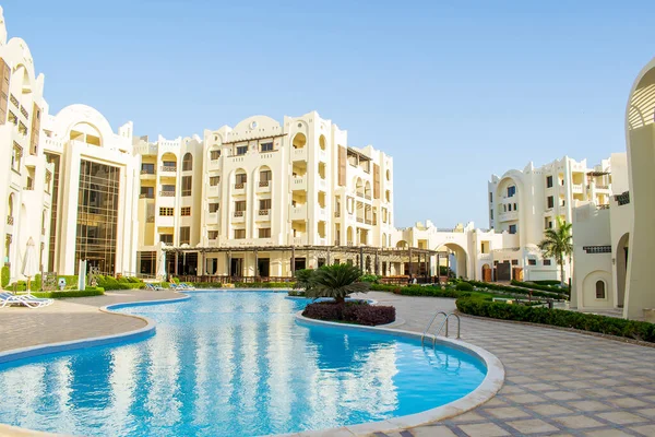 Rich luxury modern residential apartment hotel, tropical resort, swimming pool with blue clear water,green grass lawn on sunny day outdoor.Summer recreational vacation in Egypt at sea,getaway concept.