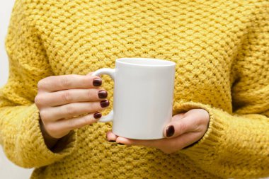 Ellerinde beyaz bardakta kahve, çay, sıcak içecek tutan bir kadın. Soğuk havada sarı, sıcak kazaklı bir kadın. Model, logo tasarımı, kopyalama alanı.