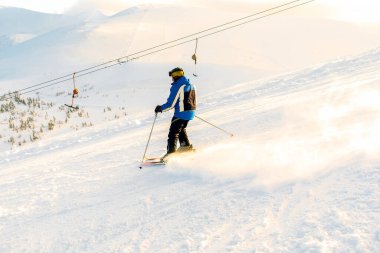 Man in winter overalls skiing on fresh powder snow hill at high Carpathian mountains in sunset light at winter alpine ski resort holiday,outdoor nature landscape, Ukraine, Europe.extreme sport.