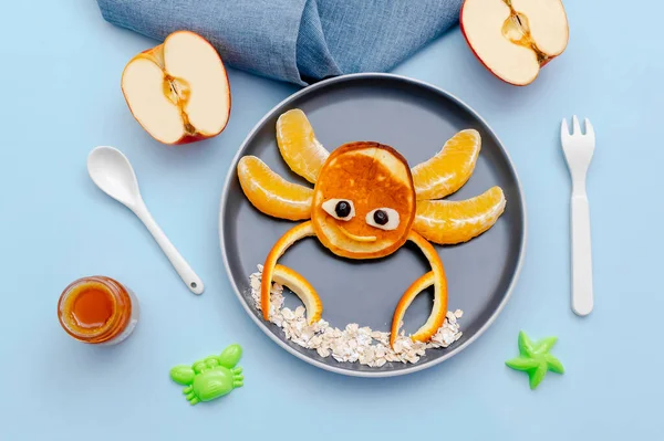 Krep, portakal, elma, tabakta bal gibi komik yengeç suratlı atıştırmalıklar. Sevimli çocuklar bebeğin tatlı tatlısını, sağlıklı kahvaltısını, öğle yemeğini, mavi arka planda yemek sanatını,.