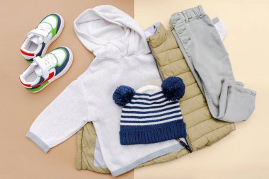 Vest,jumper,hoodie,jeans pants,hat,sneakers. Set of baby children's clothes,clothing and accessories for spring, autumn or winter on beige background. Fashion kids outfit. Flat lay,top view,overhead.