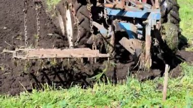 İlkbaharda çiftlikte tarımsal tarla sürme makineleri. Çiftçi bitki ve ekin ekmeden önce toprak ekip biçiyor ve ekiyor, kırsal doğa manzarası..
