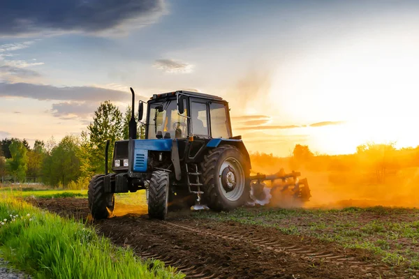 Günbatımında Ilkbaharda Çiftlikte Tarım Tarlası Sürerken Modern Mavi Traktör Makineleri - Stok İmaj