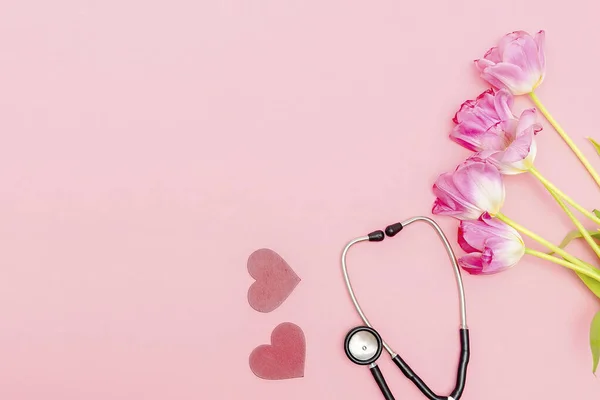 National Doctors or nurse day greeting card with stethoscope, bunch of tulips flowers on pink background.Health medicine Day.Copy space for text.mockup.