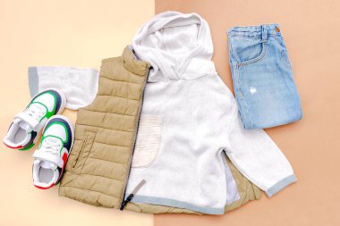 Vest,jumper,hooded sweatshirt,knitted,jeans pants with sneakers.Set of baby children's clothes,clothing,accessories for spring,autumn,winter on brown background.Fashion kids outfit.top view.