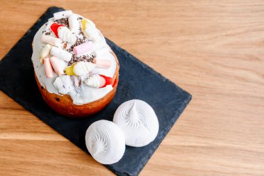 Paskalya bayramı yemekleri konsepti. Beyaz kremalı, jöleli şekerli, şekerli, şekerli, şekerli, mumlu, ahşap arka planda renkli yumurtalarla süslenmiş ev yapımı Paskalya pastası. en üstteki görünüm.