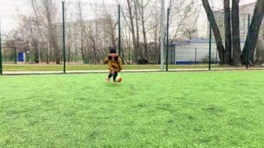 Küçük tatlı çocuk modern stadyumda futbol oynarken, parkta koşuyor. Çocuk eğlence oyunları oynuyordu. aile, çocuklar spor aktiviteleri fiziksel gelişim, çocuk yuvası.