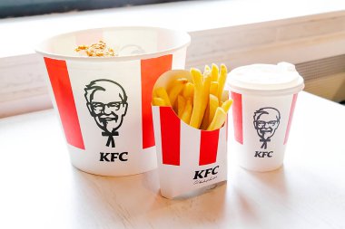 Bucket,chicken nuggets,wings,legs,Fries,coffee menu on tray in KFC restaurant.Fastfood junk food delivery,to go,takeout,take away in kraft paper eco disposable container-Kiev,Ukraine,27 December 2022