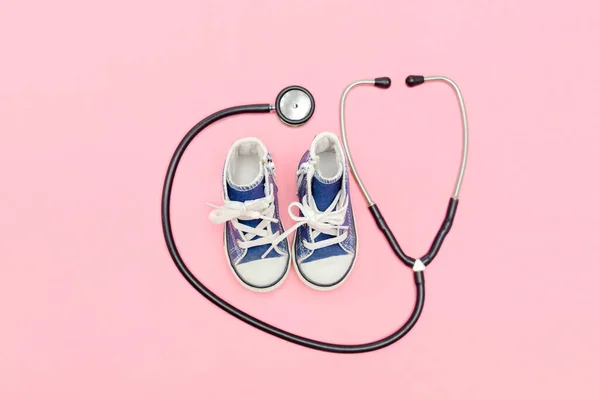 National Doctors or nurse day greeting card with stethoscope,babys childs sneakers shoes on pink background.Health medicine Day.Pregnancy,motherhood, obstetrics,pediatrics.