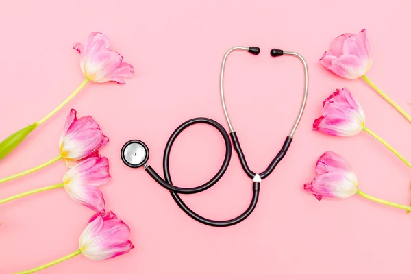 National Doctor\'s or nurse day greeting card with stethoscope, bunch of tulips flowers on pink background.Health medicine Day.Copy space for text.mockup.