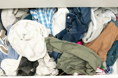 Farklı kullanılmış temiz olmayan kıyafetlerle dolu dağınık bir dolap, baştan savma itilmiş, raflarda asılı. Hızlı moda. Müsait bir yere tıkıştırılmış kirli kadın gardırobu yığını..