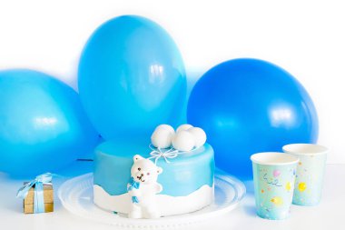 Bebeğin ilk doğum günü için kağıt bardaklar, hediye kutuları ve balonlarla süslenmiş bebek mavisi lezzetli pasta. Bebek partisi için mavi renkli süslemeler..
