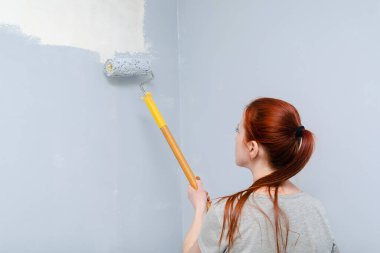 Kızıl saçlı genç bir kızın portresi, gri bir fırça rulosuyla duvarları boyayan bir kadın, yaşam, yatak odası, yeni bir daireye taşınan bir kadın sanatçı, iç mimar, bir apartman dairesi onarımı..