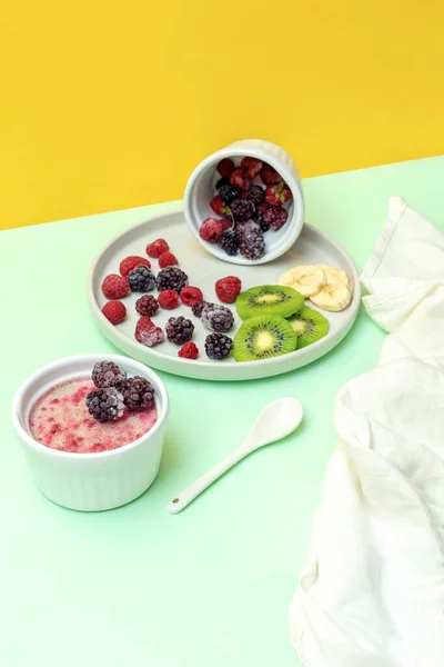 stock image Sweet ice cream yogurt with frozen banana kiwi fruits, blackberry, raspberry berries. Cold fresh summer homemade dessert food on gray plate.