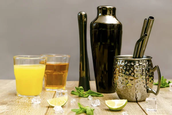 Taze buzlu limonata yaz içeceği, alkollü ya da üzümlü kokteyl, parlak yeşil nane yaprakları. Siyah karıştırıcı, bardak, ahşap masada barmen aletleri..
