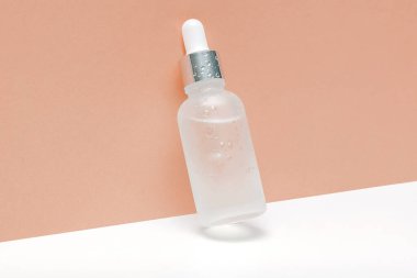Aromatik yağ ya da serum içeren cam damlası ambalajı, su damlaları. Doğal organik Spa Kozmetik Ürün Tasarımı Mockup.Ön görünüm. Bej kahverengi arka planda kopyalama alanı.