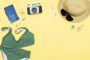 Seyahat tatili düz yatak, aksesuar nesneler, şapka, pasaport, güneş gözlüğü, kıyafet, mayo, kamera, deniz kabuğu fotokopi alanı olan sarı arka plan, planlama macerası.