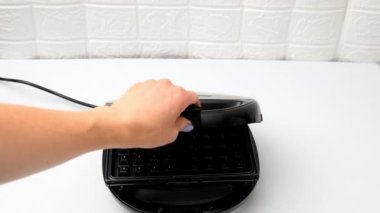 Kadın şef waffle makinesini açıyor, waffle yapmak için hamur pişiriyor, krep pişiriyor. Sabah kahvaltısı hazırlıyor, mutfak masası için yemek tarifi veriyor. Fırın, küfür teknolojisi..