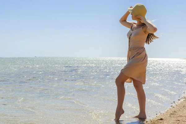 Young adult female woman person with hat enjoy relaxing on sea,walk along ocean beach,coast in luxury resort,looking on blue clear water.Summer travel tropical recreational vacation tourism concept.