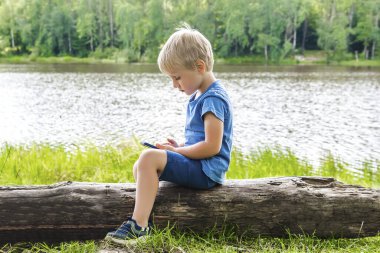 Çocuk çocuk sırtüstü oturur, boynuna, telefonuna bakar. Düzgün eğimli pozisyon pozisyonu, vücut hizası. Skolyozu önleme. Omurga problemi..