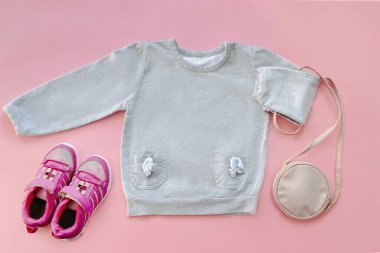 Warm gray jumper,sweater,sneakers,purse,little bag.Set of baby children's clothes,clothing for spring,autumn,winter on pink background.Casual fashion girls kids outfit.Flat lay,top view,mockup.