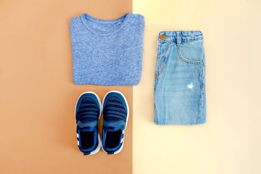 Bebek ayakkabısı, tişört, kot pantolon. Bahar, sonbahar için çocuk kıyafetleri aksesuarları. Moda çocuk kıyafetleri, bej rengi kahverengi arka plan..