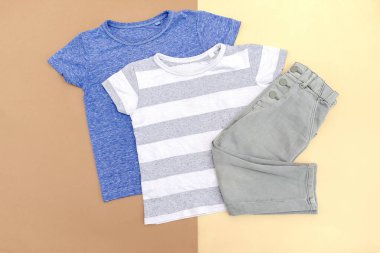Bebek tişörtü, kot pantolon. Bahar, sonbahar, yaz için çocuk kıyafetleri. Moda çocuk kıyafetleri, bej kahverengi arka planda kıyafetler..