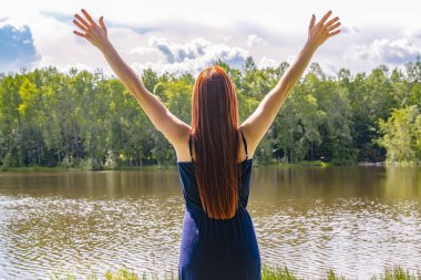 Kollarını açmış meditasyon yapan, göl, nehir, zihin rahatlatıcı, detoksifikasyon gibi hayaller kuran genç ve narin kız turistin arka planı..