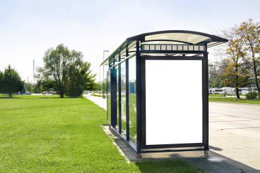 Şehir caddesindeki toplu taşıma durağı barınağının yanındaki reklam panosunda boş beyaz reklam panosu afişi, caddelerdeki yollar..
