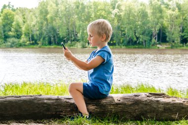 Çocuk çocuk sırtüstü oturur, boynuna, telefonuna bakar. Düzgün eğimli pozisyon pozisyonu, vücut hizası. Skolyozu önleme. Omurga problemi..