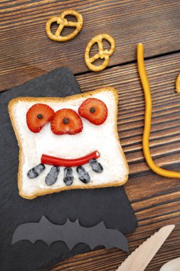 Cadılar bayramında kızarmış ekmek, tereyağı, çilek, şeker, servis masası, siyah arka planda yarasalar. Çocuklar için tatlı öğle yemeği..