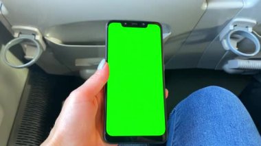 Cep telefonu yeşil ekran krom tuş tarayıcısı kullanan bir kadın el, uçakla, trenle yolculuğa hazırlanıyor. Yolculuk, tatil. Yaz tatili planlama.