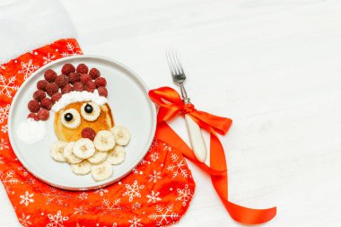 Noel Baba gözlemesi, ahududulu, muzlu, çocuklara kırmızı çorap çocuk kahvaltısı. Beyaz arka planda yeni yıl süslemeleri olan xmas yemekleri