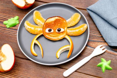 Krep, portakal, tabakta elma şeklinde komik yengeç suratlı atıştırmalıklar. Sevimli çocuklar bebekler tatlı tatlı tatlı tatlı tatlı, sağlıklı kahvaltı, öğle yemeği, ahşap arka planda yemek sanatı, üst manzara.