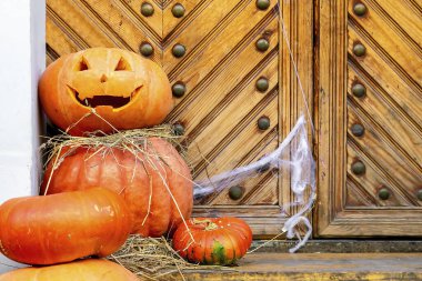 Spooky Halloween carved pumpkin face.Funny pumpkin decoration design on stairs,staircase,doorstep,porch of building,house entrance,hallows eve.Thanksgiving holiday. clipart