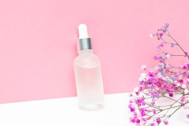 Cam damlası ambalajı aromatik yağ ya da serum, parfüm, çiçek dalı pembe arka planda. Doğal organik spa ürünleri mockup.flat lay, kopyalama alanı