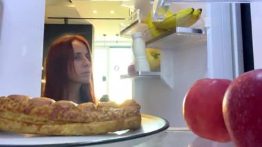 Mutfakta aç bir kadın var. Etrafa bakıyor, tatlı çörek yiyor, sağlıksız besleniyor, diyet bozukluğu, kilo kontrolü, obezite aşırı yemek alışkanlığı.